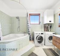 Bathroom with a bathtub, shower, washing machine, and dryer in a family house.