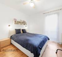 Bedroom in a family house with a bed, wooden floor decor, and a TV on the wall.