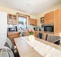 A kitchen in a family house with wooden decor furniture and equipment, floral decoration on the table.