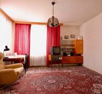 Living room in a family house with a red carpet, an armchair, and curtains on the windows.