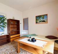 Living room in a family house with carpeted floor, wooden furniture, and a picture of a beach.