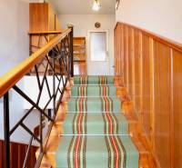 A staircase with carpet and wooden panels in a family house, with a door at the end of the hallway.