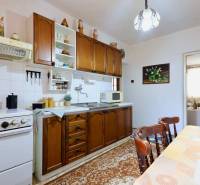 A kitchen in a family house with wooden cabinets, a dining table, and kitchen appliances.