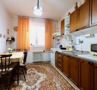 Traditional kitchen in a family house with wooden cabinets and orange curtains.