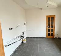 An empty room in a two-room apartment, dark tiled floor, white walls, wooden doors.