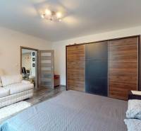 A bedroom in a family house with a wood-decor floor, a large wardrobe, and a comfortable sofa.