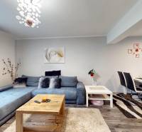 Living room in a family house with a blue sofa, dining table, and floor with a wooden decor.