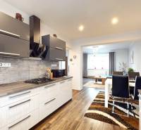 A kitchen in a family house with a wooden decor floor and a dining table.