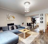 Living room with wood-patterned flooring, gray sofa, and dining table in a family house.