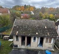A family house in Pruské with a worn-out roof, a yard, and autumn nature in the background.