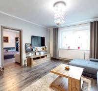 Living room in a family house with a fireplace, wooden decor flooring, and a sofa set.