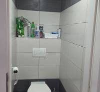 A toilet with tiles and storage space in a 3-room apartment.