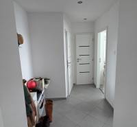 Hallway in a 3-room apartment with gray tiles, a shoe cabinet, and shoes on the floor.