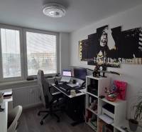 A study in a 3-room apartment with a desk, a shelf, a painting, and a floor with a wooden decor.
