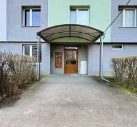 Entrance to the apartment building on Leningradská Street in Michalovce, surrounded by bushes.