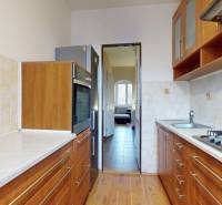 A kitchen in a 3-room apartment with a wooden decor floor and light tiles.