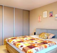 Bedroom in a family house with a bed, built-in wardrobe, and decorative paintings on the wall.