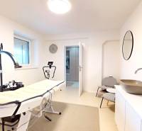 Interior of a family house with a massage table, sink, mirror, and chairs.