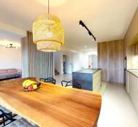 A kitchen in a family house with a wooden table, a sofa, and modern lighting.