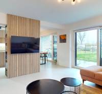 Living room with large windows, a comfortable sofa, and wooden decor on the wall.