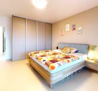 A bedroom in a family house with a colorful bedspread and a large built-in wardrobe.