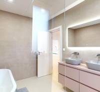 A bathroom with a bathtub, two sinks, and a mirror in a family house.