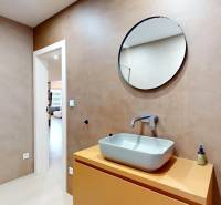 A bathroom in a family house with a sink, a round mirror, and a shower corner.