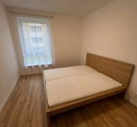 A bedroom with a bed, a floor with a wooden decor in a 2-room apartment.