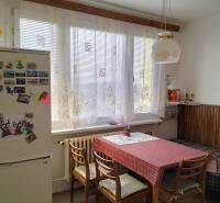 A kitchen in a 2-room apartment with a dining table, chairs, and a fridge with magnets.