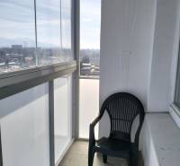 Glazed balcony with a view and a plastic chair, part of a 2-room apartment.