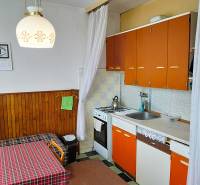 A kitchen with older furniture in a 2-room apartment, orange cabinets, table, chandelier.