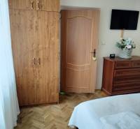 A bedroom in a two-room apartment with a wooden decor floor, a wardrobe, and a television.