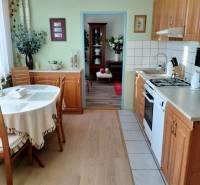 A kitchen in a 2-room apartment with a wooden decor floor and a table in the corner of the room.