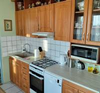 A kitchen in a 2-room apartment with wooden cabinets, a stove, and appliances.