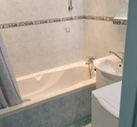 Bathroom in a 2-room apartment with a bathtub and light tiles.