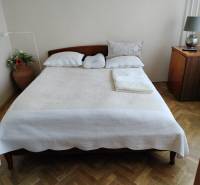 Bedroom with a double bed, wood-patterned flooring, and a nightstand in a two-room apartment.