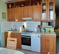 A kitchen in a 2-room apartment with a wooden decor, equipped with appliances and storage space.