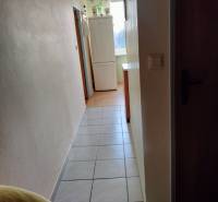 A hallway with a refrigerator in a 2-room apartment, tiled floor, light-colored walls.