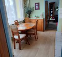 Dining area in a 2-room apartment with a wooden decor floor and light furniture.