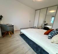 Bedroom in a 2-room apartment with a bed, a desk, and a mirrored wardrobe.