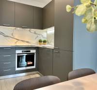 A kitchen in a 2-room apartment with stone cladding and gray cabinets.