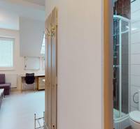 Offices with a corner sofa, table, shower, and wooden decor on the wall.