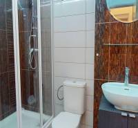 Bathroom with a modern shower, sink on a cabinet, and toilet in the offices.