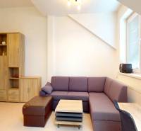 The photograph of the office is dominated by a purple sofa and light wooden decorations.