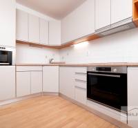 A kitchen in a 3-room apartment with white cabinets and a wood-patterned floor.