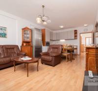 Living room with a leather sofa, dining table, and kitchen, 3-room apartment, floor with wooden decor.