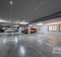 Underground parking lot with marked parking spaces and parked cars and motorcycles.