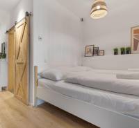 A bedroom in a studio apartment with sliding doors and a wood-patterned floor.