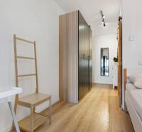 Interior of a 1-room apartment with a wooden decor floor, wardrobe, and bed.