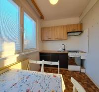 A kitchen in a 2-room apartment with a wooden decor floor and a dining table.